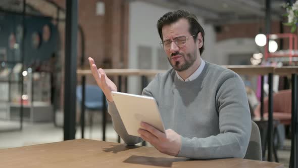 Young Man Reacting to Loss on Tablet While Sitting in Office