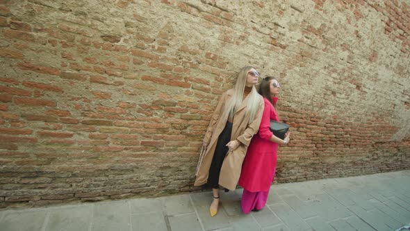 Young Women Hold Purses Standing Near Shabby Wall in Venice