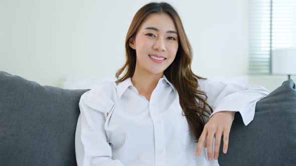 Portrait of Asian  young Beautiful girl in pajamas smile and look at camera from bed in bedroom.