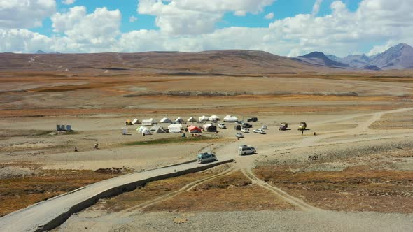 Aerial drone of vans carrying cargo and tourists arriving at a campground in the high-altitude alpin