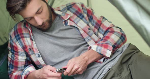 Close Up of Young Man Playing with His Swiss Army Knife After Hiking. Beautiful Man Relaxing in a