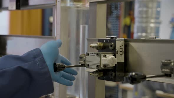 Student with gloves pushing lever of hydraulic machinery in scientific laboratory. Static close up s