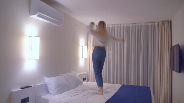 A woman is dancing on the bed to the music.