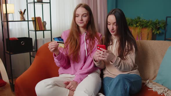Cheerful Girls Friends Using Credit Bank Card and Smartphone While Transferring Money Purchases