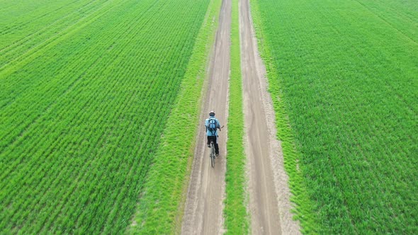 An Aerial View of a Cyclist Riding Along a Rural Path Surrounded By Green Fields