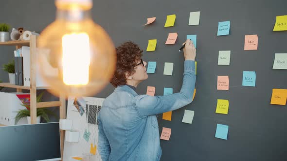 Slow Motion of Office Worker Writing on Bright Sticky Notes Planning Marketing Strategy in Workplace