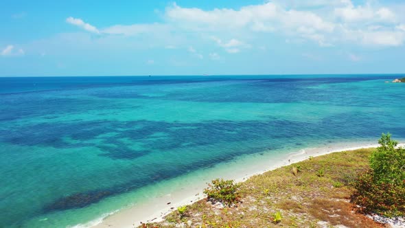 Aerial travel of tranquil seashore beach voyage by transparent ocean with bright sandy background of