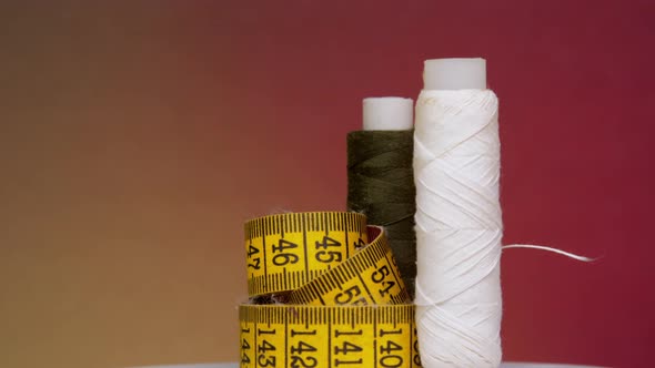 Yellow Measuring Tape and Spool with White Thread Rotate