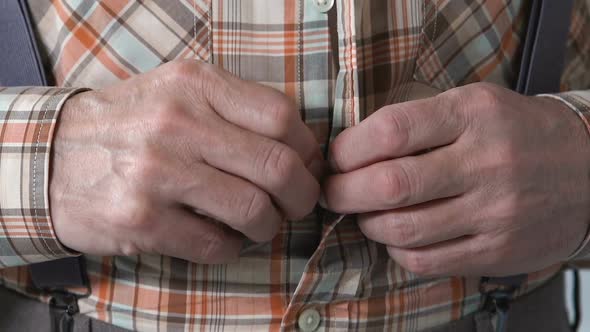 Male Pensioner With Shaking Hands Buttoning Up Shirt, Parkinson Tremor Disease