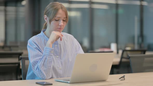 Young Woman Thinking While Working on Laptop in Office