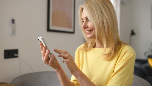 Happy Senior 50s Woman Spends Leisure Time Online Holding Smartphone