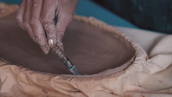 Potter Forming Clay Into a Dish By Using a Form and Tools To Get the Perfect Shape