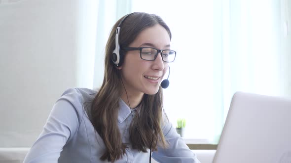 Young Woman Wearing Headphones Communicating Online Via Laptop Explaining Teaching