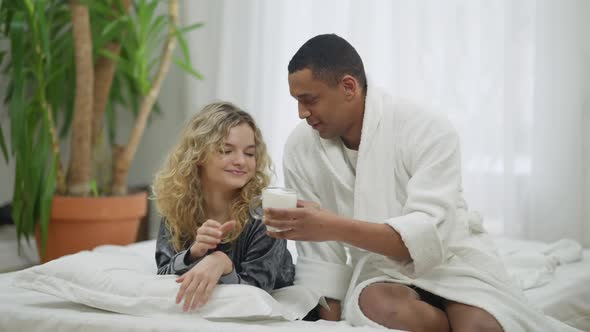 African American Loving Man Bringing Morning Coffee for Caucasian Woman in Bed