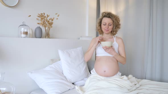 Pregnant Woman Having Dinner Eating Soup In Bed.