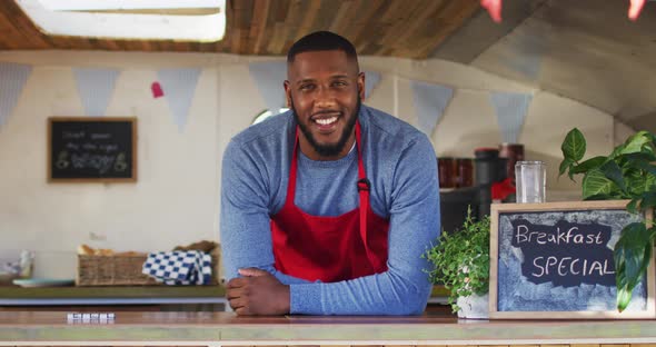 Portrait of african american man wearing apron smiling while standing in the food truck