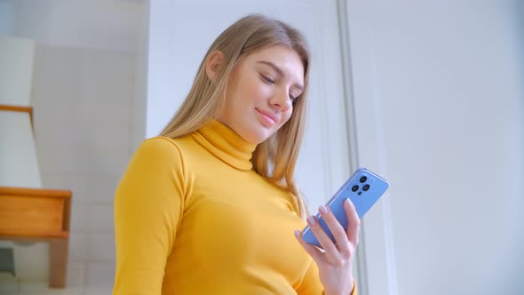 Happy white female browsing internet on modern blue smartphone with triple camera in 4k video