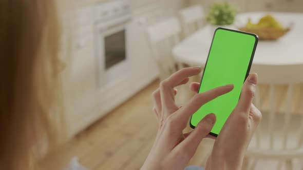 Handheld Camera Back View of Blond Woman Holding Chroma Key Green Screen Smartphone Watching Content