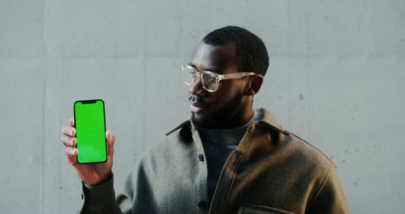 African American Man Looking at Camera Holding Mobile Phone with Green Screen