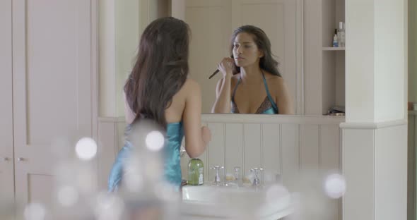 Woman looking into mirror and applying make-up