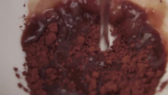 hot stream of water is poured into a white mug with cocoa powder