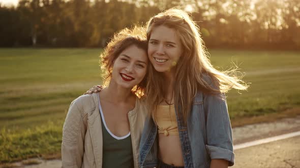 Portrait of Young Beautiful Blonde and Adorable Asian Brunette Looking to the Camera and Smiling