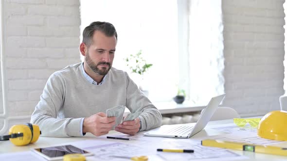 Hardworking Young Architect Counting Dollars in Office