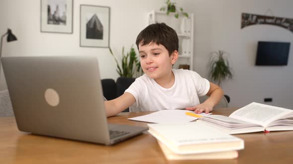 Smiling Schoolboy Studying on the Distance From Home Using Trendy Laptop