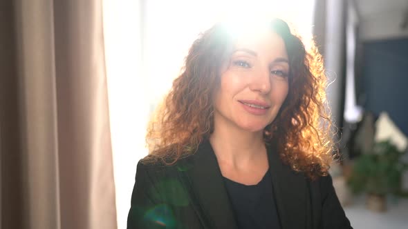 Curly Business Woman in a Black Business Suit Looking at the Camera While Smiling While Standing in