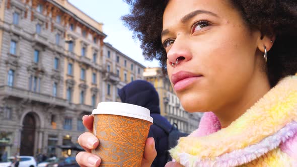 Young beautiful curly hair black woman outdoor in the city drinking a coffee to go