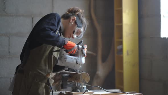 Female carpenter cutting wood with fretsaw