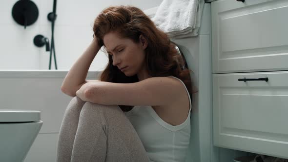 Caucasian woman with problems sitting on the floor in the bathroom. Shot with RED helium camera in 4