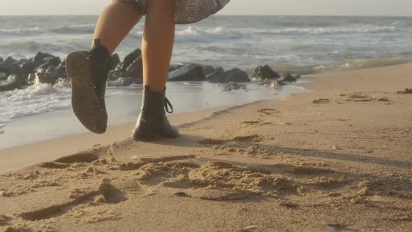 Closeup Cinematic Shot of Woman Feet in Boots Walking on the Beach at Sunset or Sunrise