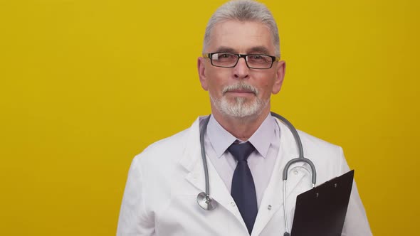 Adult Doctor Man in Glasses and a Medical Gown with a Stethoscope Shows of Pill Closeup Holding