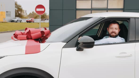 New White Luxury Car with Big Red Bow Riding Out of Modern Auto Salon