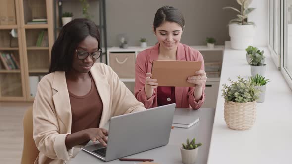 Two Mixed-race Businesswomen Working Together in Office