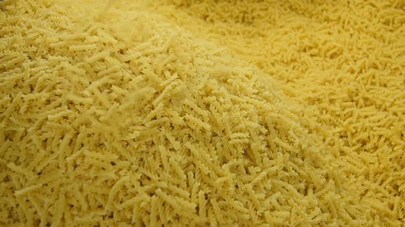 Spiral Pasta Spilling Over a Pile of Dry Macaroni