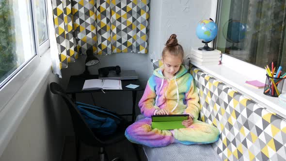 Cozy Little Balcony. A Girl in Pajamas Looking For Information Using a Tablet