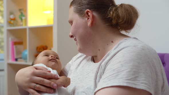 Overweight Caucasian Mother Rocking Adopted Mixed Race Infant at Home