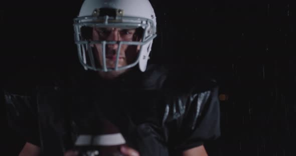 Portrait of the Determined Professional American Football Player in Dark Night Holding the Ball