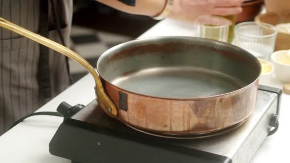 Crop cook adding oil on pan