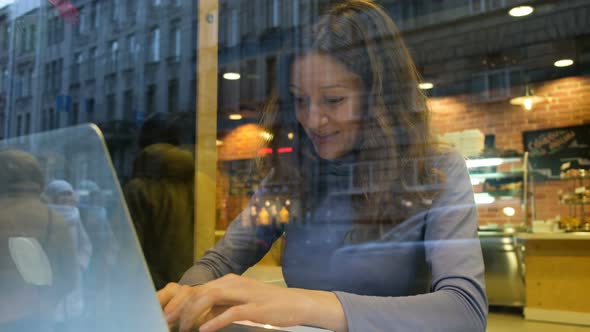 Beautiful Freelance Girl Works Hard at the Cafe at the Computer and Drinks Coffee, .