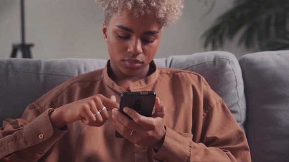 African Woman Resting on Couch with Smart Phone Enjoy Modern Wireless Device