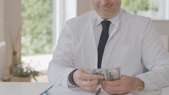 Unrecognizable Happy Doctor Counting Dollars and Smiling. Satisfied Caucasian Male Physician