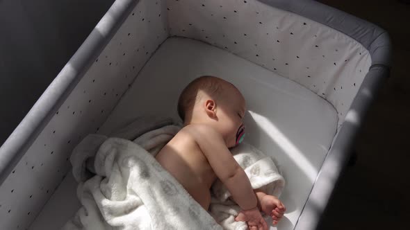 Top View Face of Newborn Nnaked Sleeping Little Small Infant Baby Boy Lying On Side On Soft White