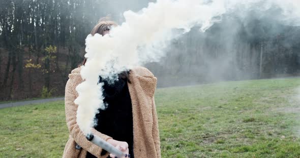 Woman Makes Emergency Flare Signal with White Smoke. Hipster Pretty Girl with Smoke Bomb