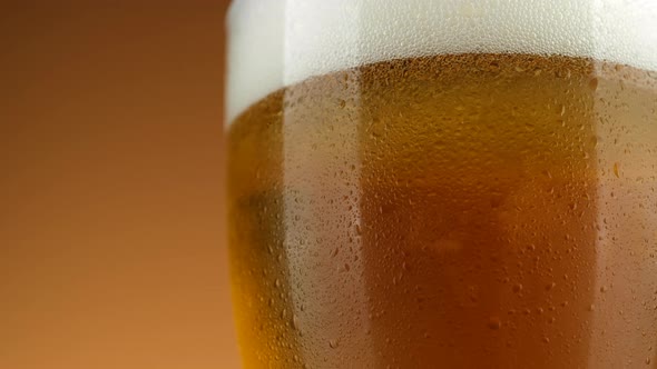 Cold Glass of beer close up with froth, rotation. Cold Light Beer in a glass with water drops