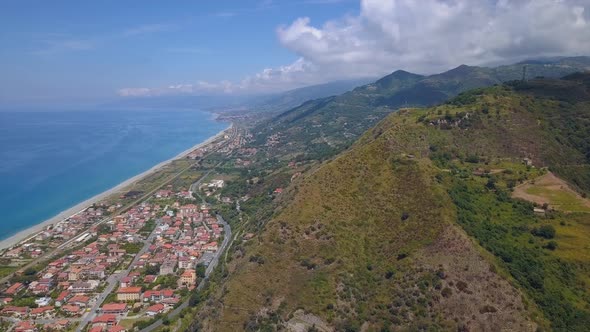 Aerial View of Hill Overlooking Sea Coast Village and Mountains. Flight Over Gorge, Sunny Day