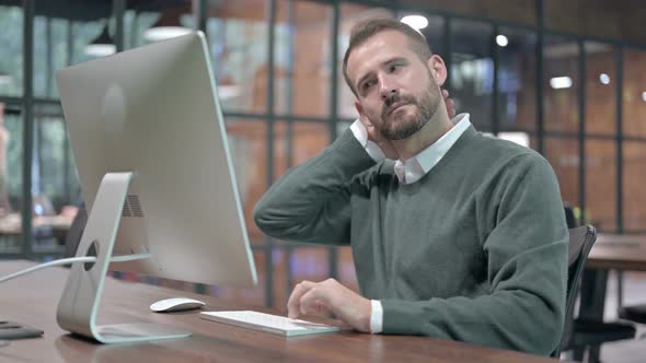 Tired Man Having Neck Pain While Working on Computer