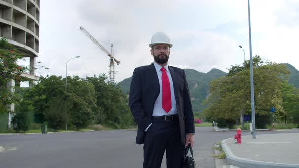 Portrait of an Engineer in White Protective Helmet in a Business Suit with Red Tie with a Briefcase